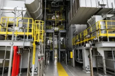 Industrial processing equipment with yellow safety railings and access platforms