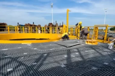 Workers installing FRP grating panels on an industrial platform